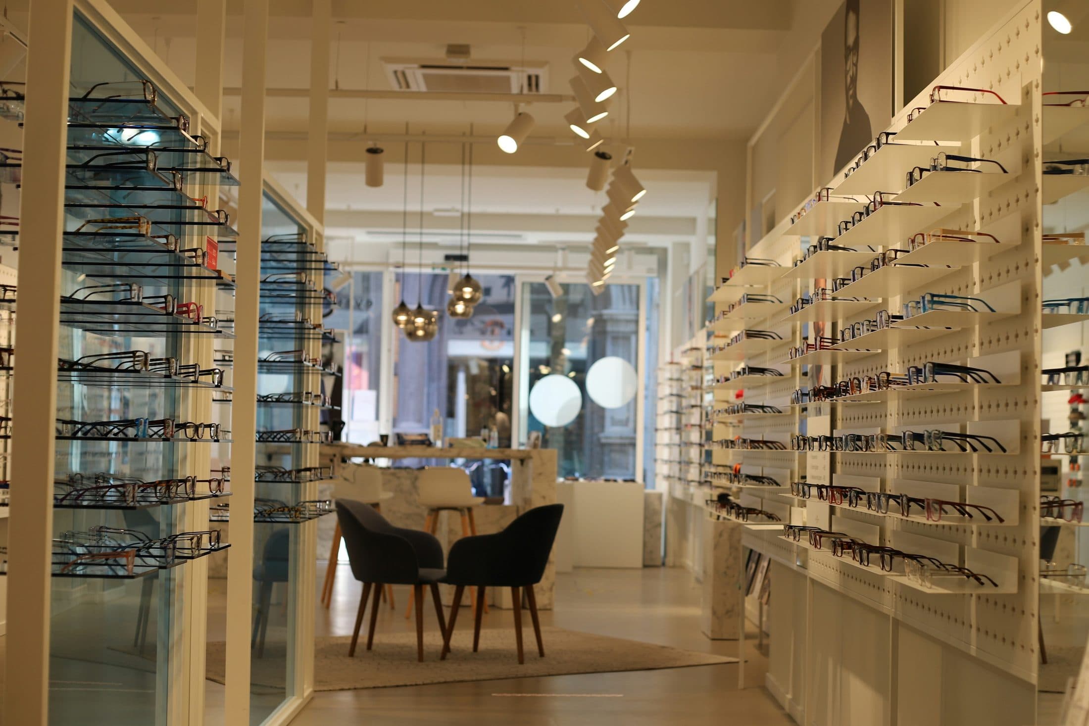 Intérieur lumineux d'une boutique d'optique : murs garnis de montures, vitrines et fauteuils
